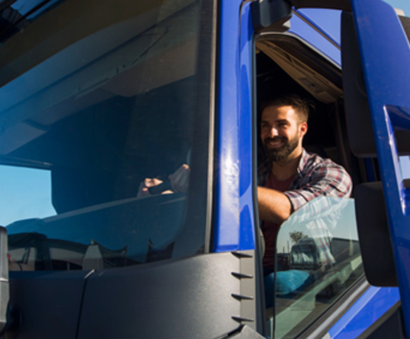 caminhão azul com motorista branco de barba sorrindo
